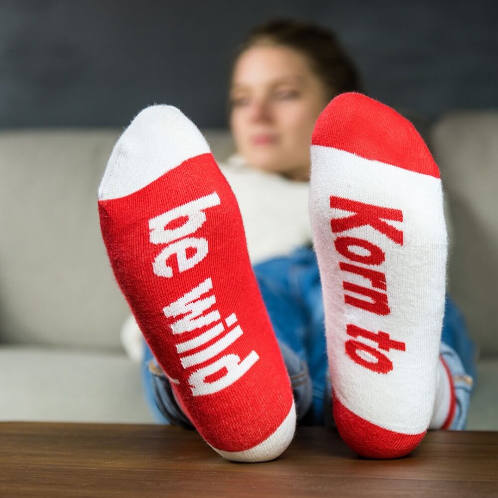 Frau auf Sofa trägt Berentzen Socken, Aufdruck von unten: Korn to be wild