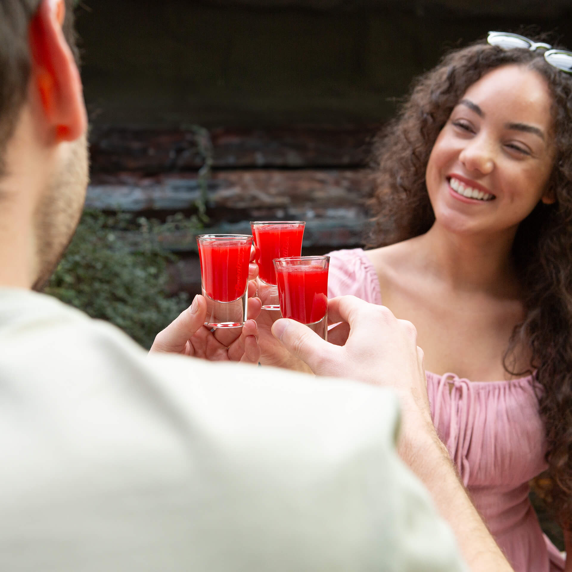 Freunde stoßen mit Shotgläsern von Berentzen Smoothie Shot Fruity an