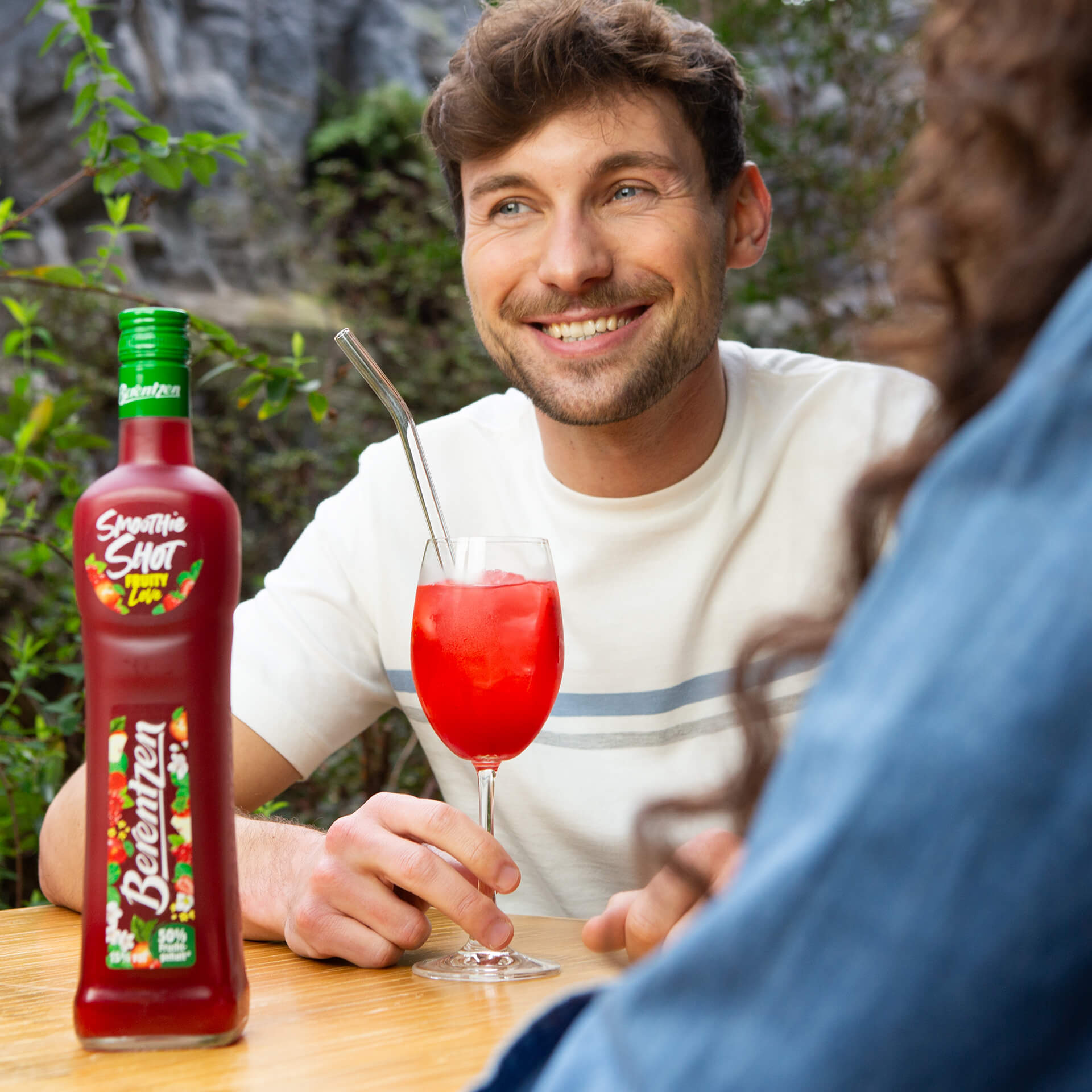Mann hält Glas mit Berentzen Smoothie Shot Fruity