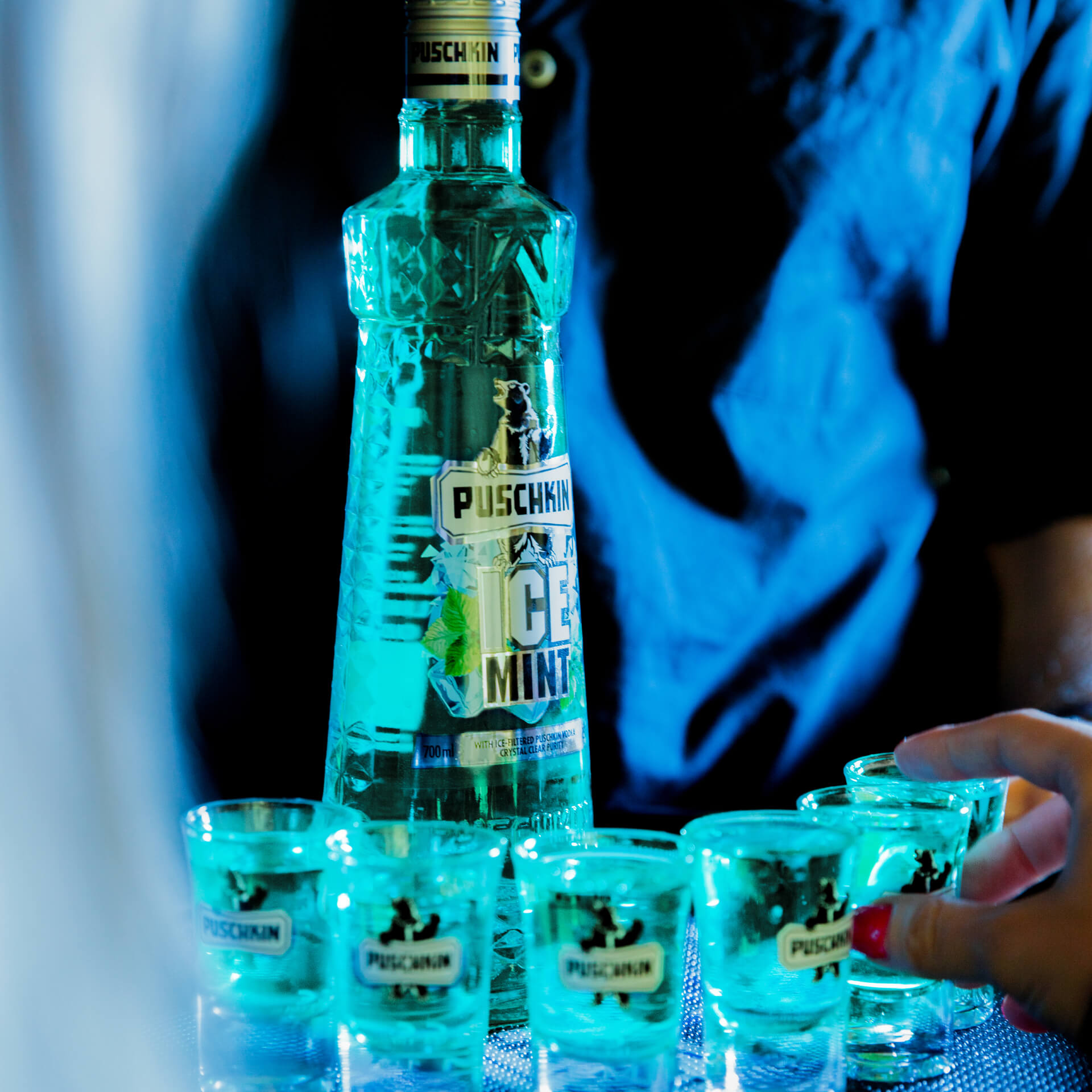 Puschkin Ice Mint Flasche Puschkin Ice Mint in einer Bar neben mehreren befüllten Shotgläsern