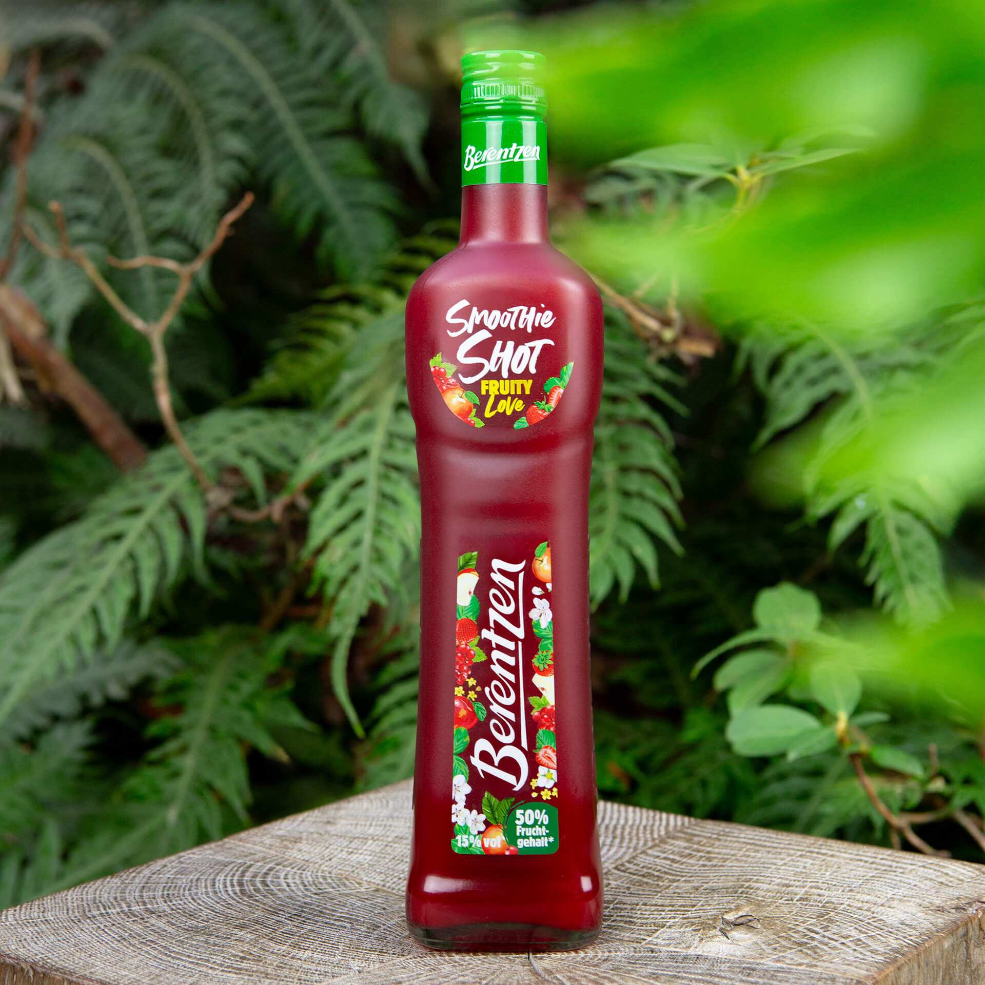 Berentzen Smoothie Shot Fruity Love Flasche Berentzen Berry Kiss vor Sträuchern