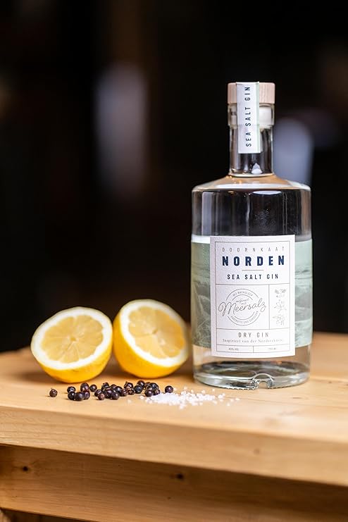 Flasche Norden Sea Salt Gin steht auf Tisch neben Zitronen und Salzkörner